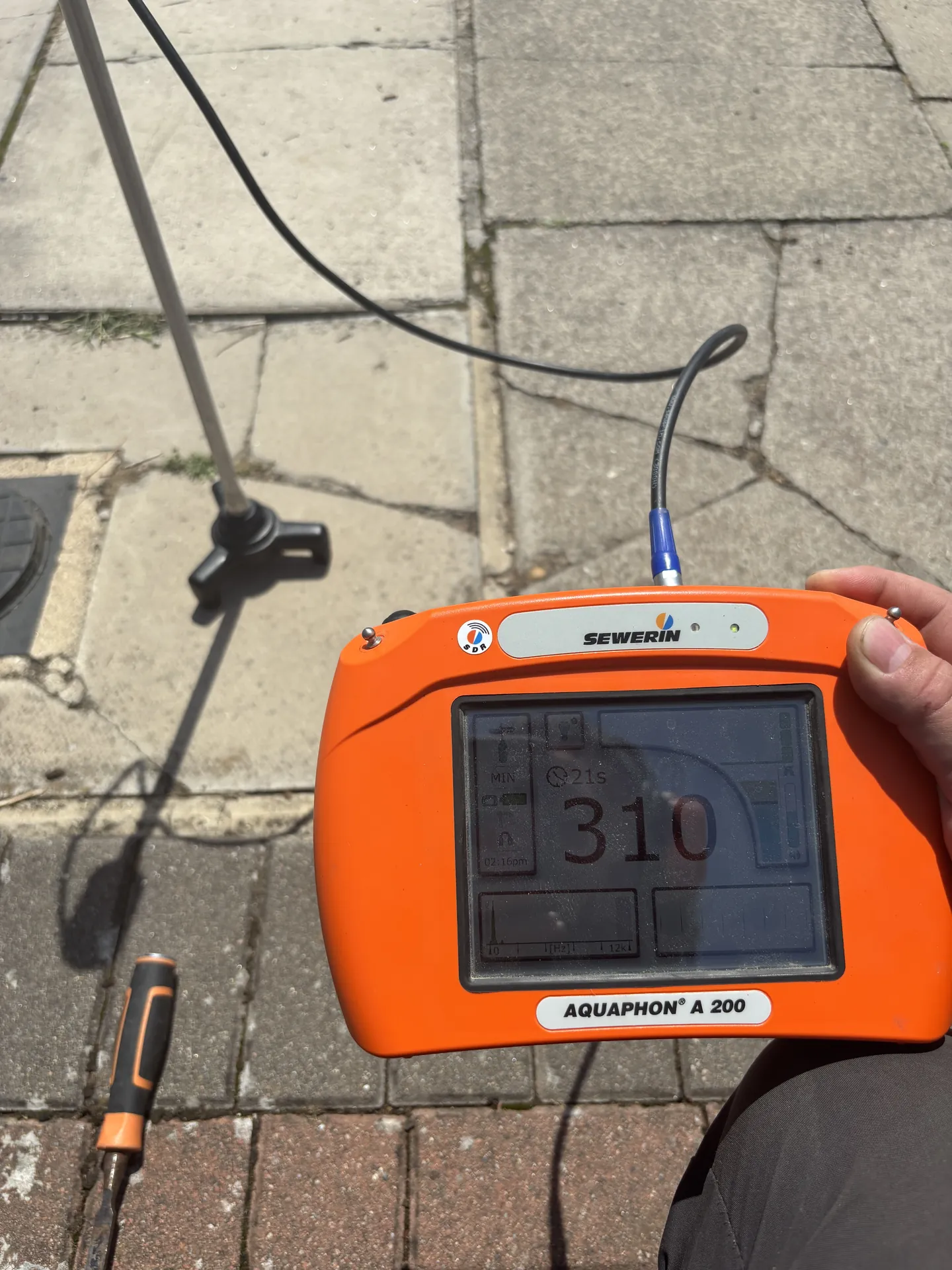 Acoustic leak detector reading 310 on block paving over a buried supply pipe