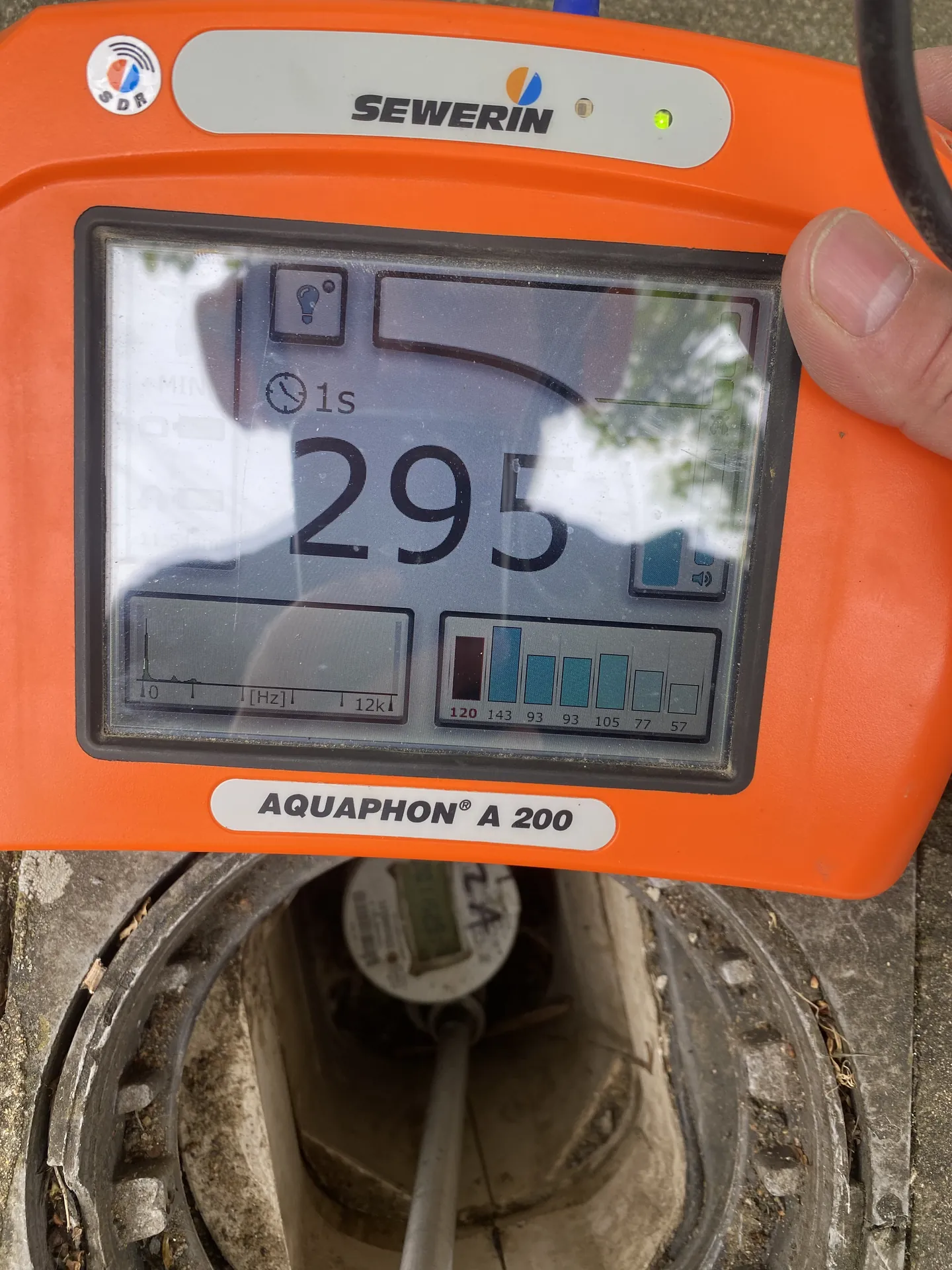 Close-up of an acoustic leak detector screen reading 295 over a suspected leak