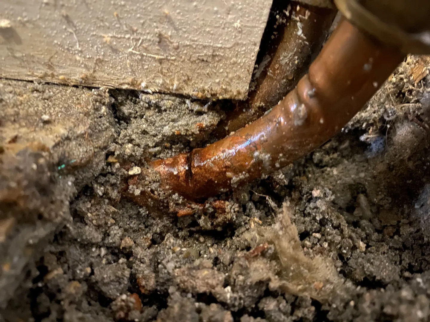 Corroded copper pipe found leaking under a floor