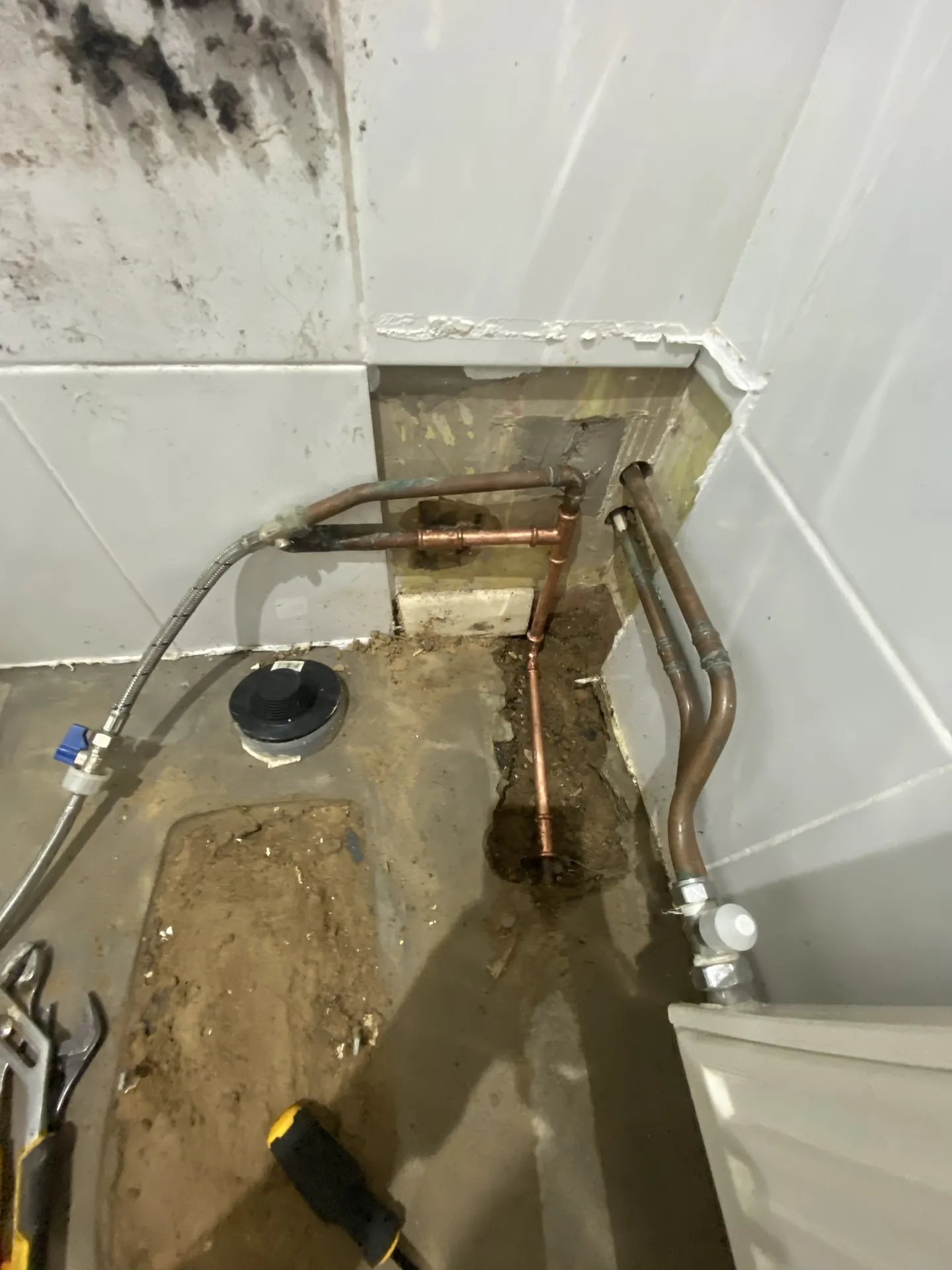 Floor void under a bath opened to show the leaking pipework