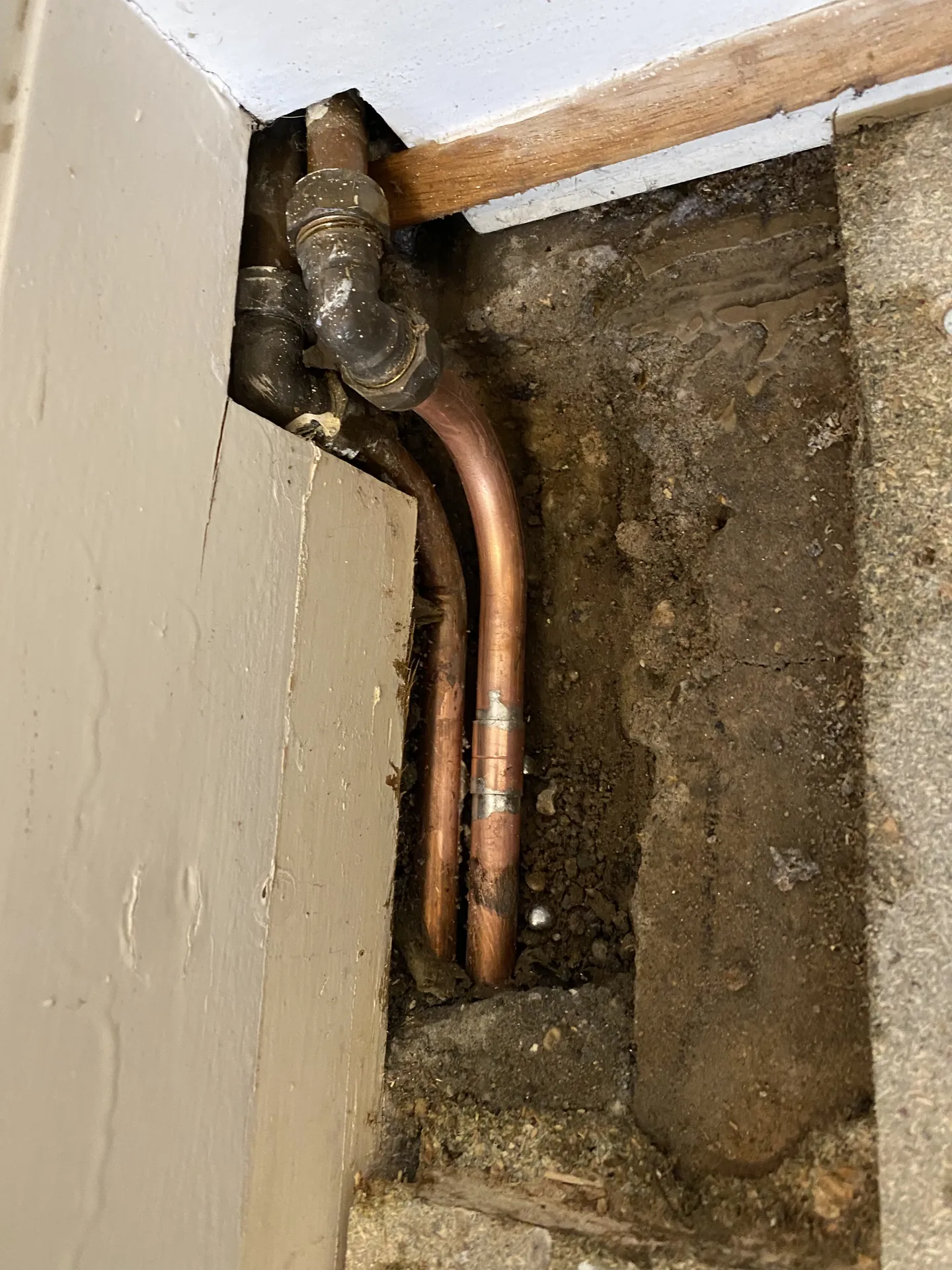 Copper pipes exposed in a small wall chase for a leak repair