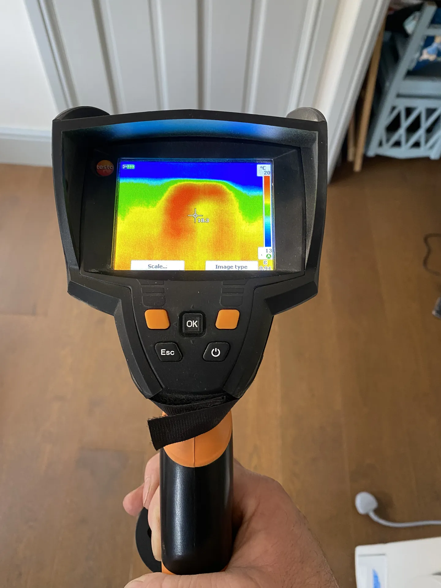Thermal camera in hand showing a hot spot where a heating pipe is leaking