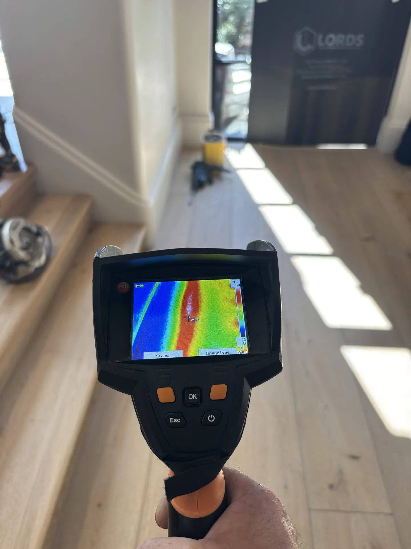 Thermal camera picking out a pipe under a wooden floor by a doorway