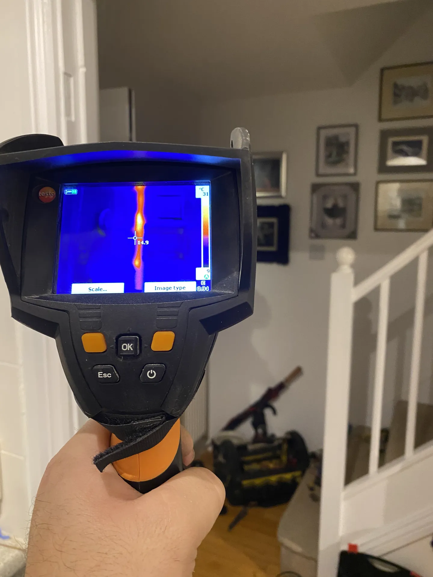 Engineer scanning a hallway wall with a thermal imaging camera during a leak survey