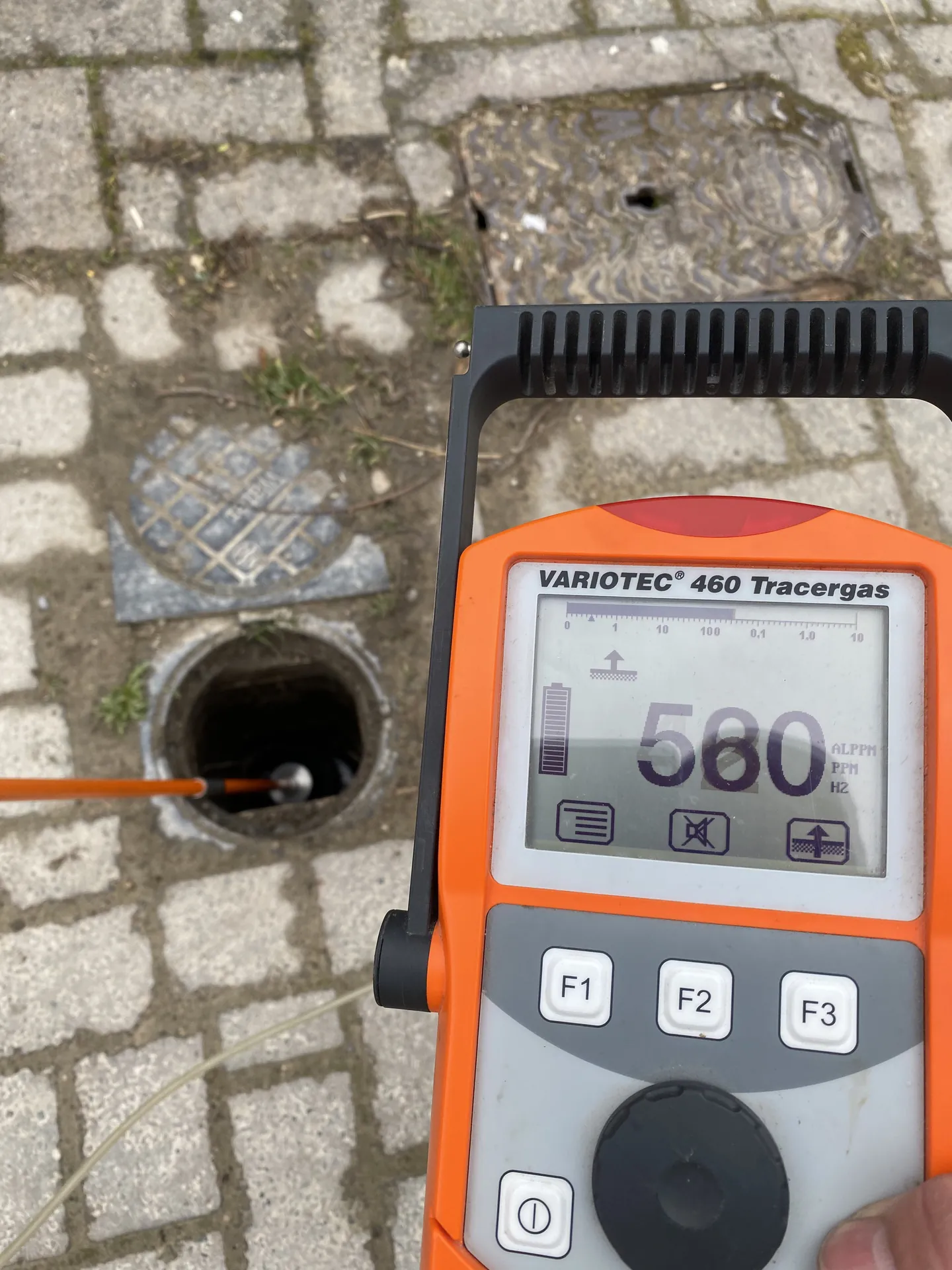 Tracer gas detector reading 580 at an inspection chamber on block paving
