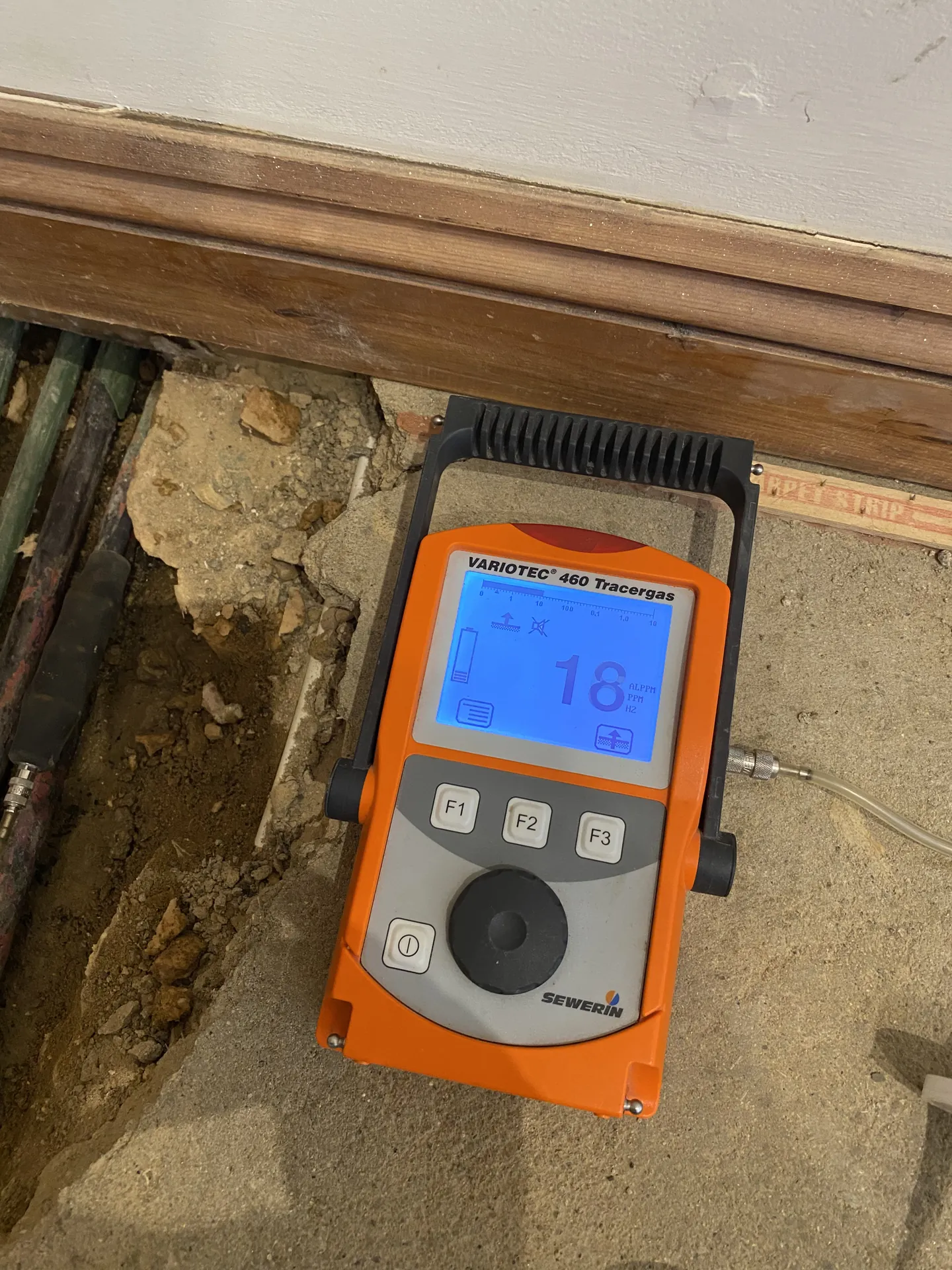 Tracer gas detector at an opened pipe chase in a wall