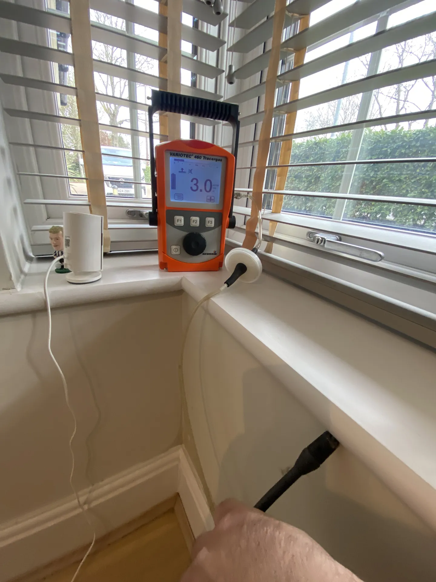 Tracer gas detector on a window sill with the probe checking a pipe run below
